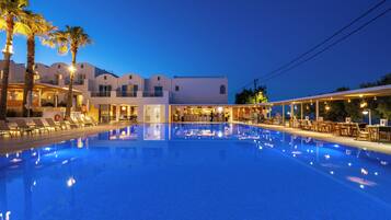 Una piscina al aire libre, sombrillas, sillones reclinables de piscina