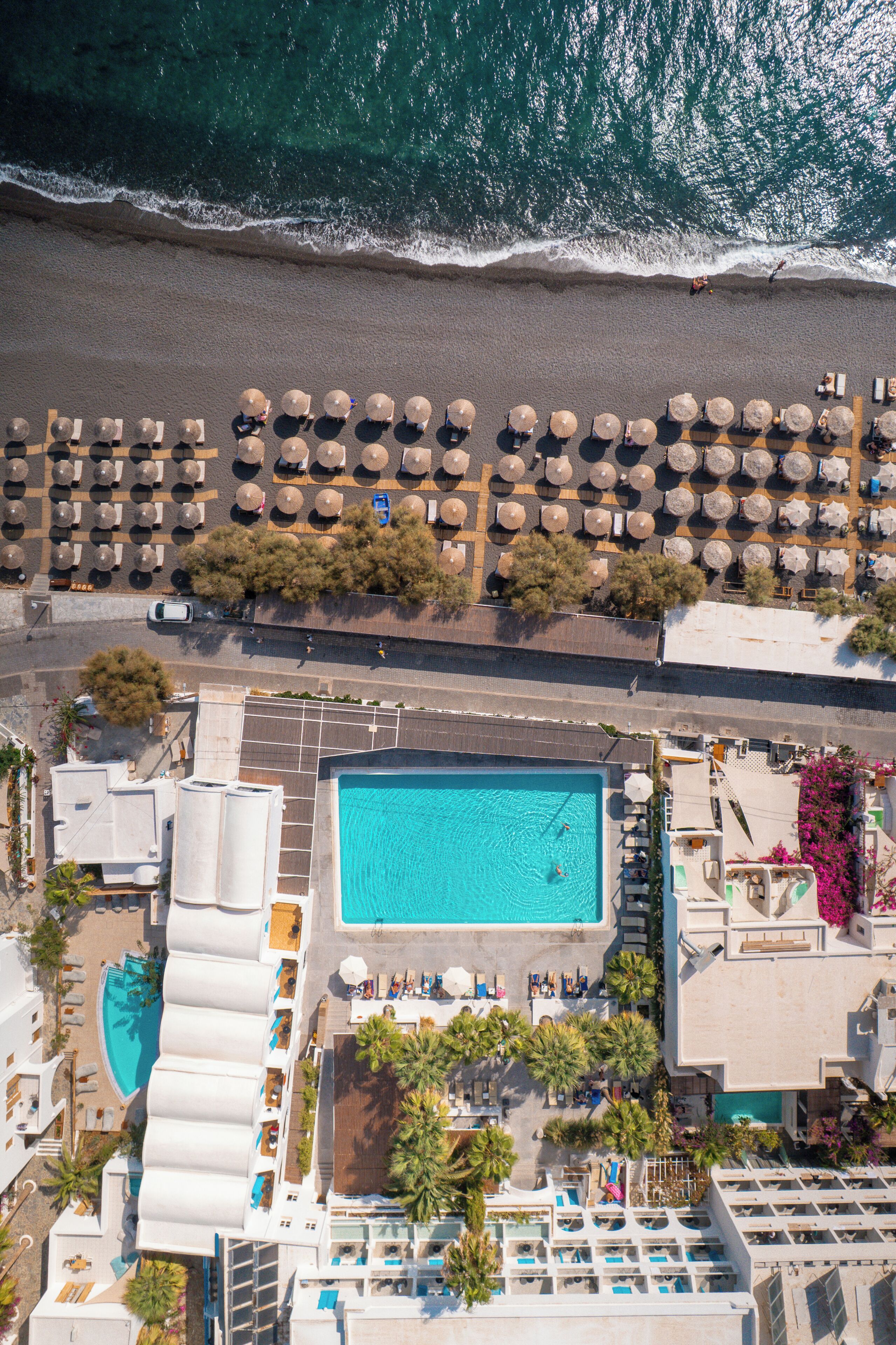 Vista aérea de un resort con piscina, sombrillas de playa y sillas de descanso.