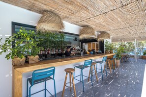Zona de bar con mostrador de madera, sillas azules y lámparas colgantes.