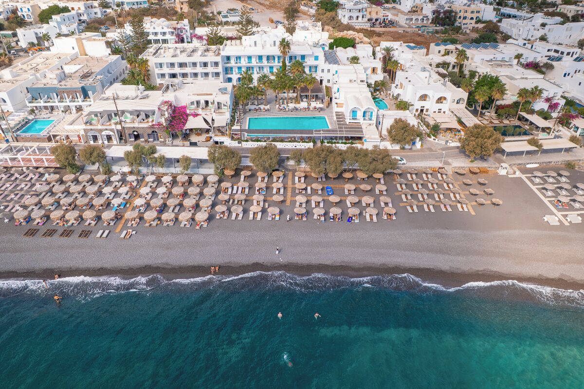 An aerial view of a coastal hotel with a beach, pool, and multiple rooms.