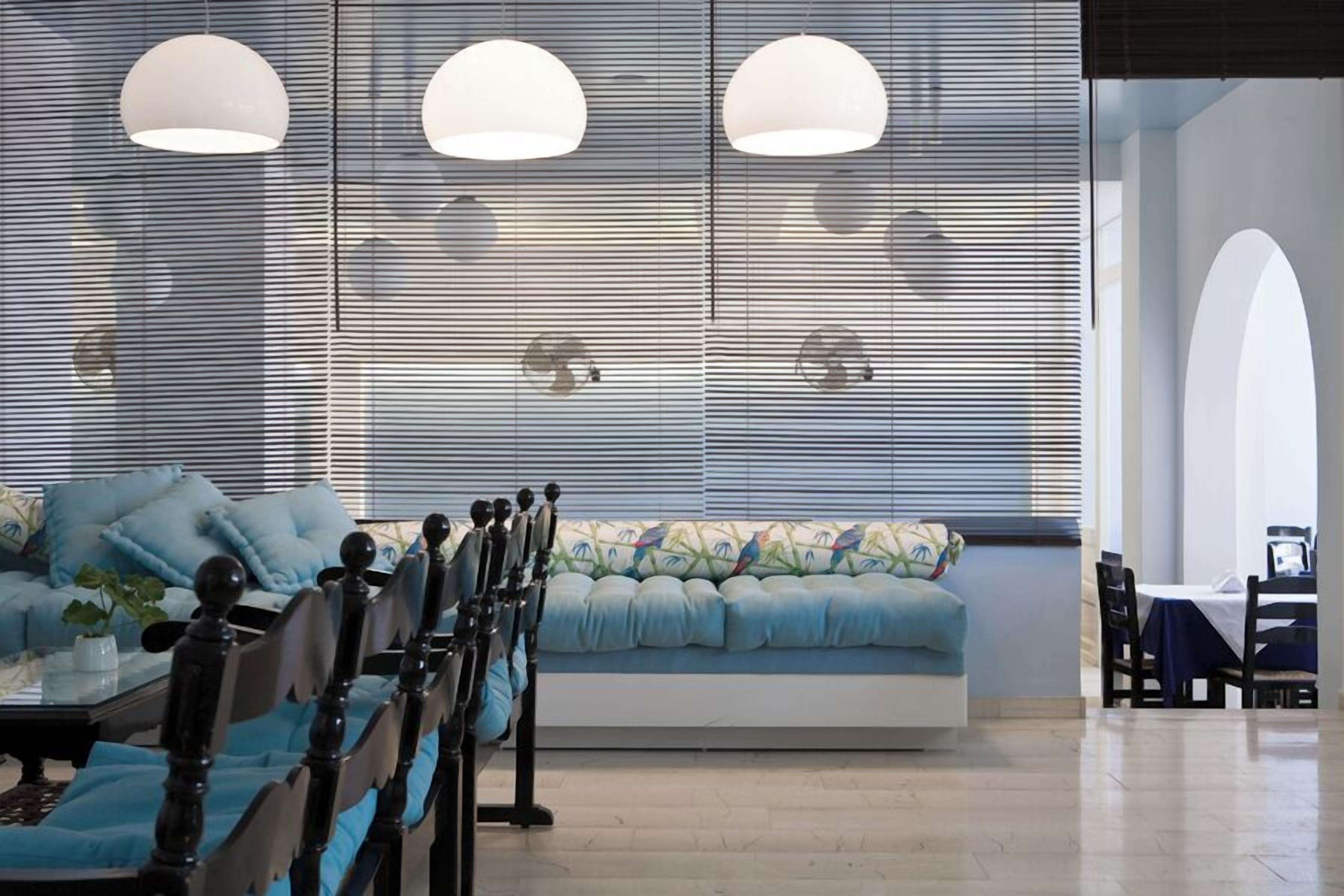 Un interior moderno con un sofá, una mesa de comedor, sillas e iluminación colgante.