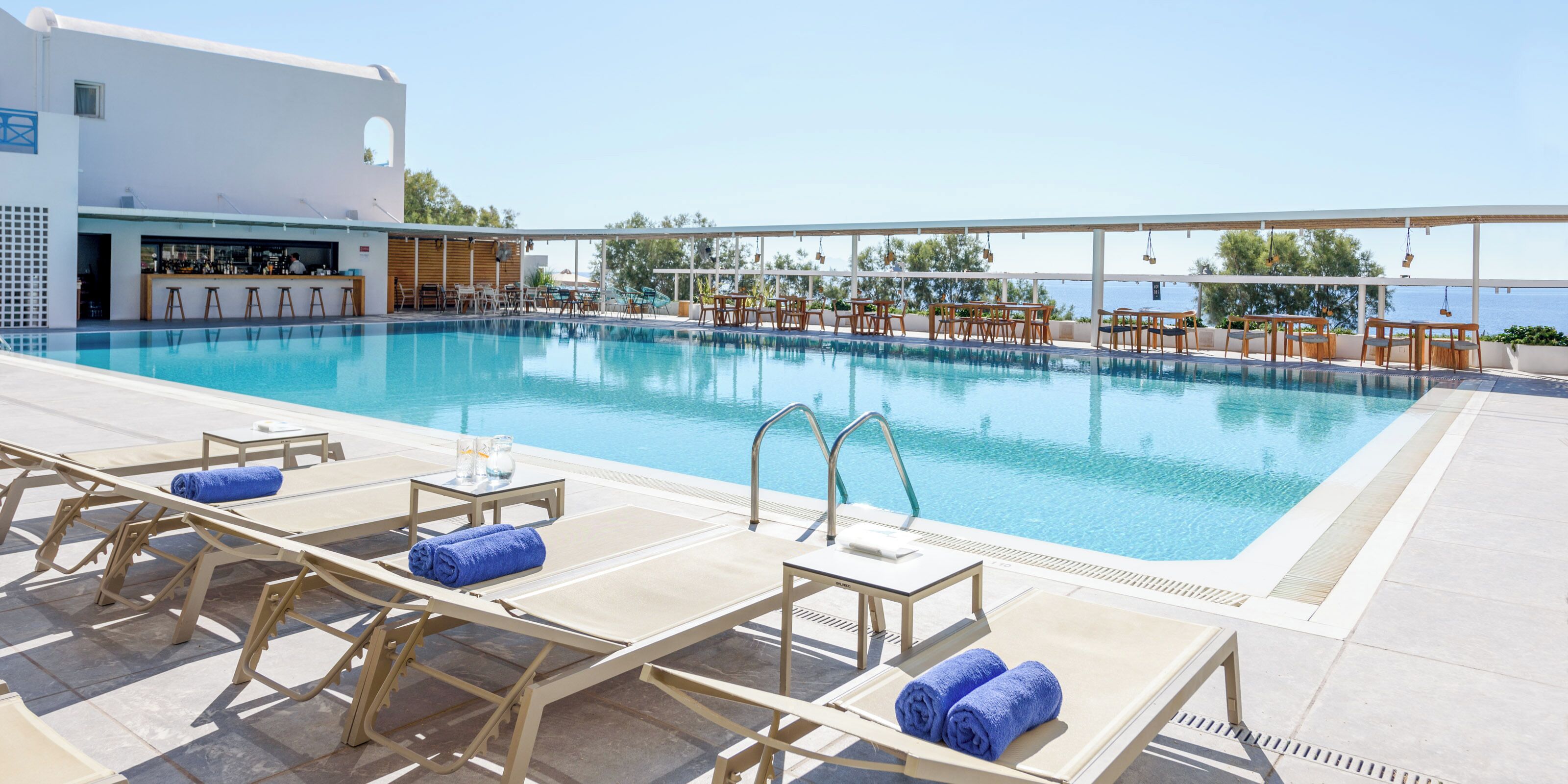 A pool area with lounge chairs and a bar.