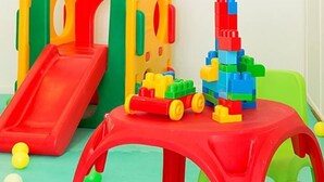 Un área de juegos con un tobogán rojo, bloques de construcción coloridos y una pequeña mesa roja.