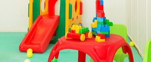 A play area with a red slide, colorful building blocks, and a small red table. - Kamari Beach Hotel (Santorini)