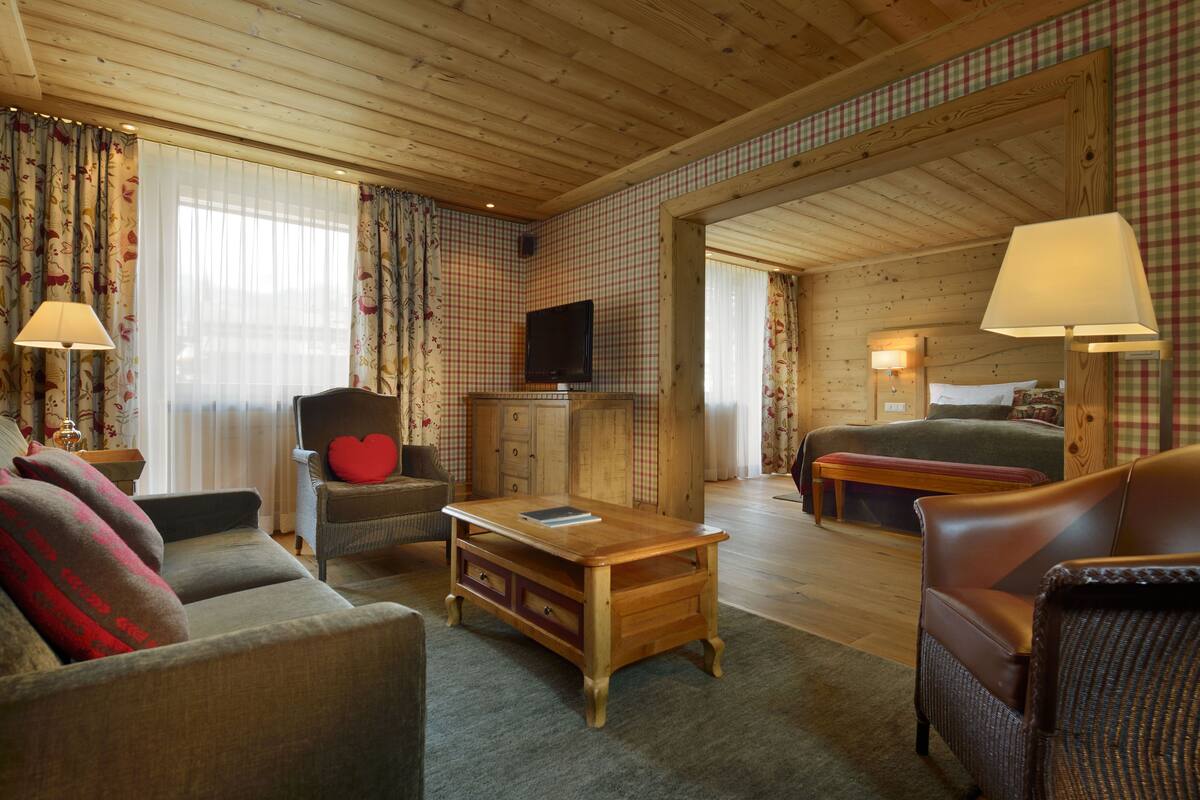 A cozy room with a sofa, armchair, wooden coffee table, and a bed.