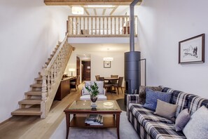 A spacious living area with a wooden staircase, a fireplace, a dining area, and a cozy seating area.