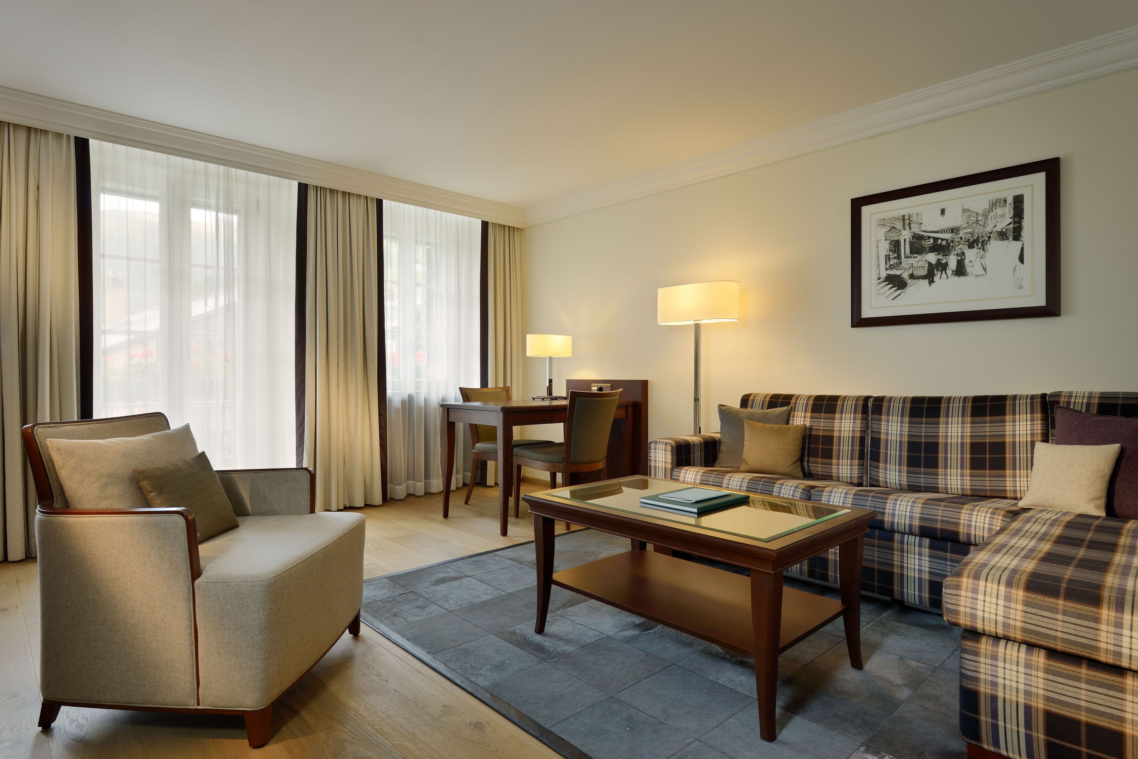 Une chambre d’hôtel équipée d’un canapé, d’un fauteuil, d’une table à manger et d’une lampe.