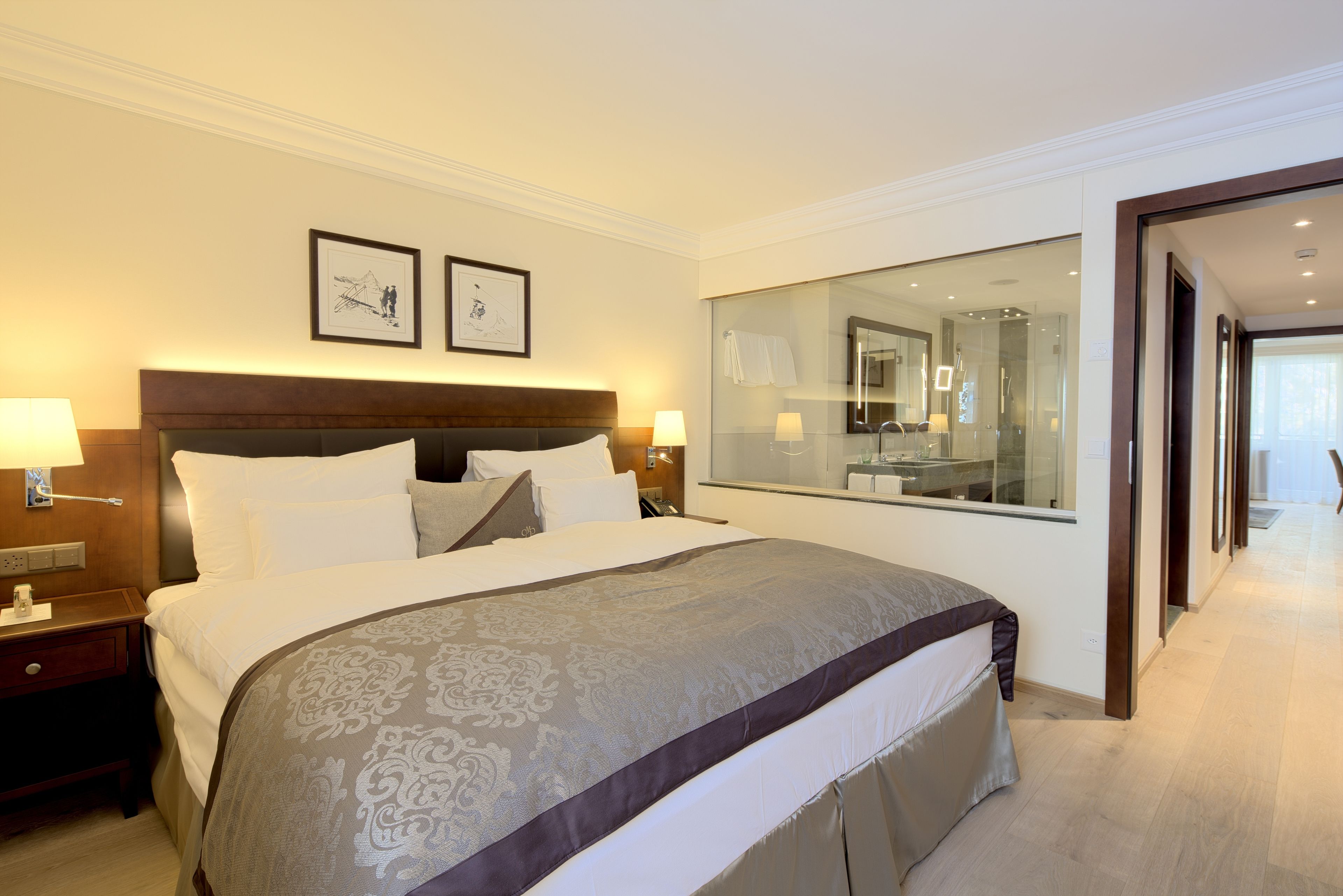 A hotel room with a large bed, a nightstand, a mirror, and a view of the bathroom.