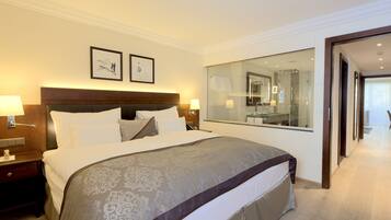 A hotel room with a large bed, a nightstand, a mirror, and a view of the bathroom.