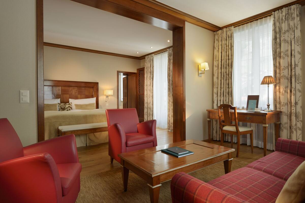 A hotel room with a bed, a desk, a chair, and a sofa.