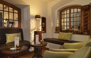 A cozy seating area with a sofa and chairs, a small table with a candle, and a decorative wooden shelf.