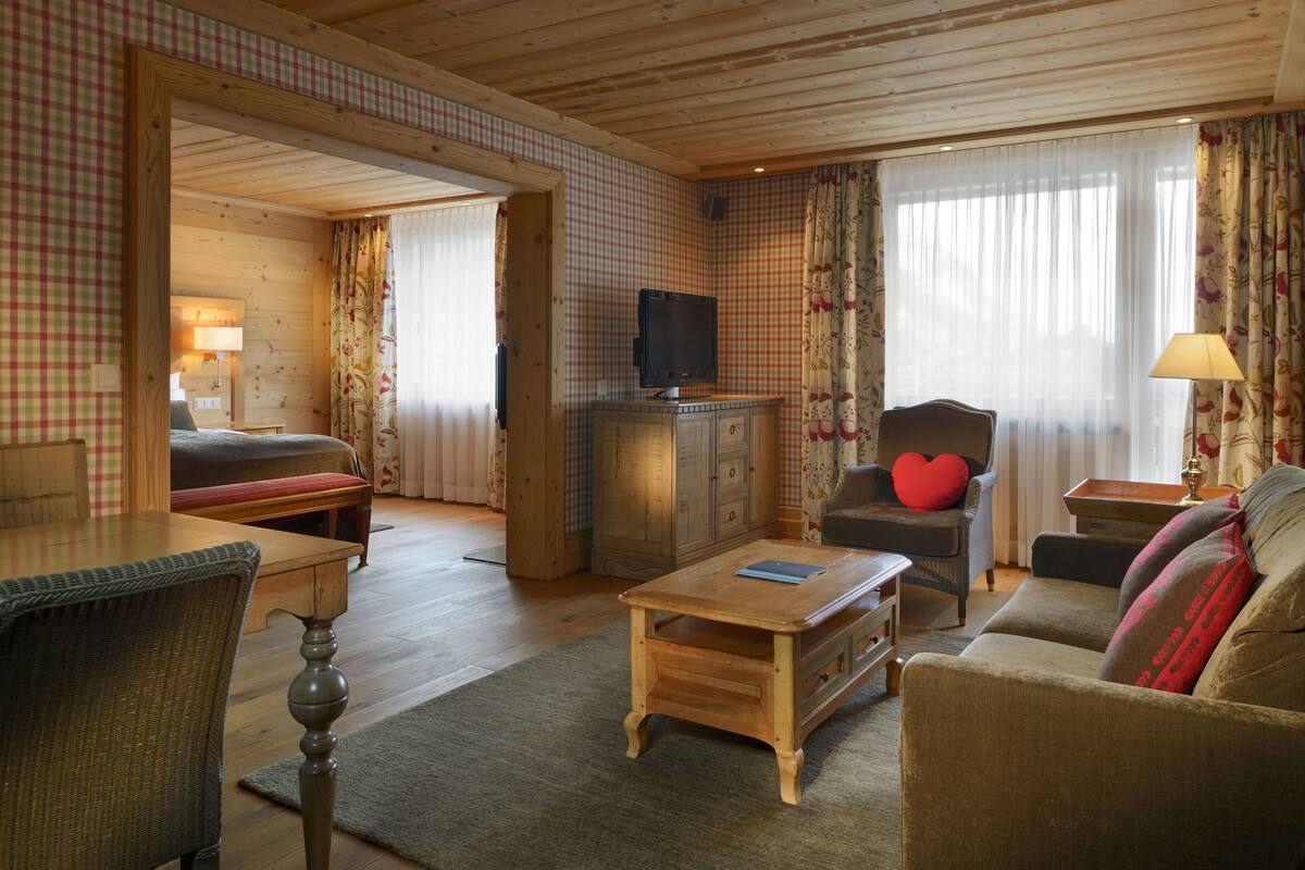 A cozy living room with a wooden ceiling, a television, a sofa, a chair, and a table.