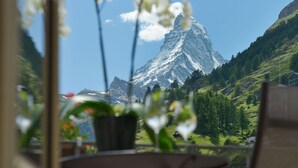 A mountain view with a house in the foreground and a mountain peak in the background. - Mont Cervin Palace (Zermatt)