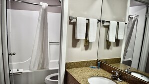 Et badeværelse med badekar, toilet, vask og et spejl.