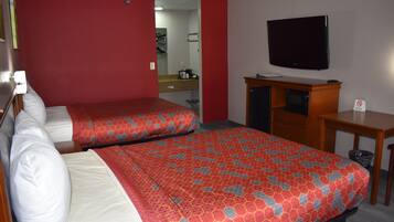 A hotel room with two beds, a TV, a desk, and a mirror.