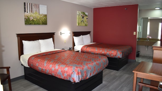 Et hotelværelse med to senge, en træsenggavl, et natbord, et skrivebord og et spejl.