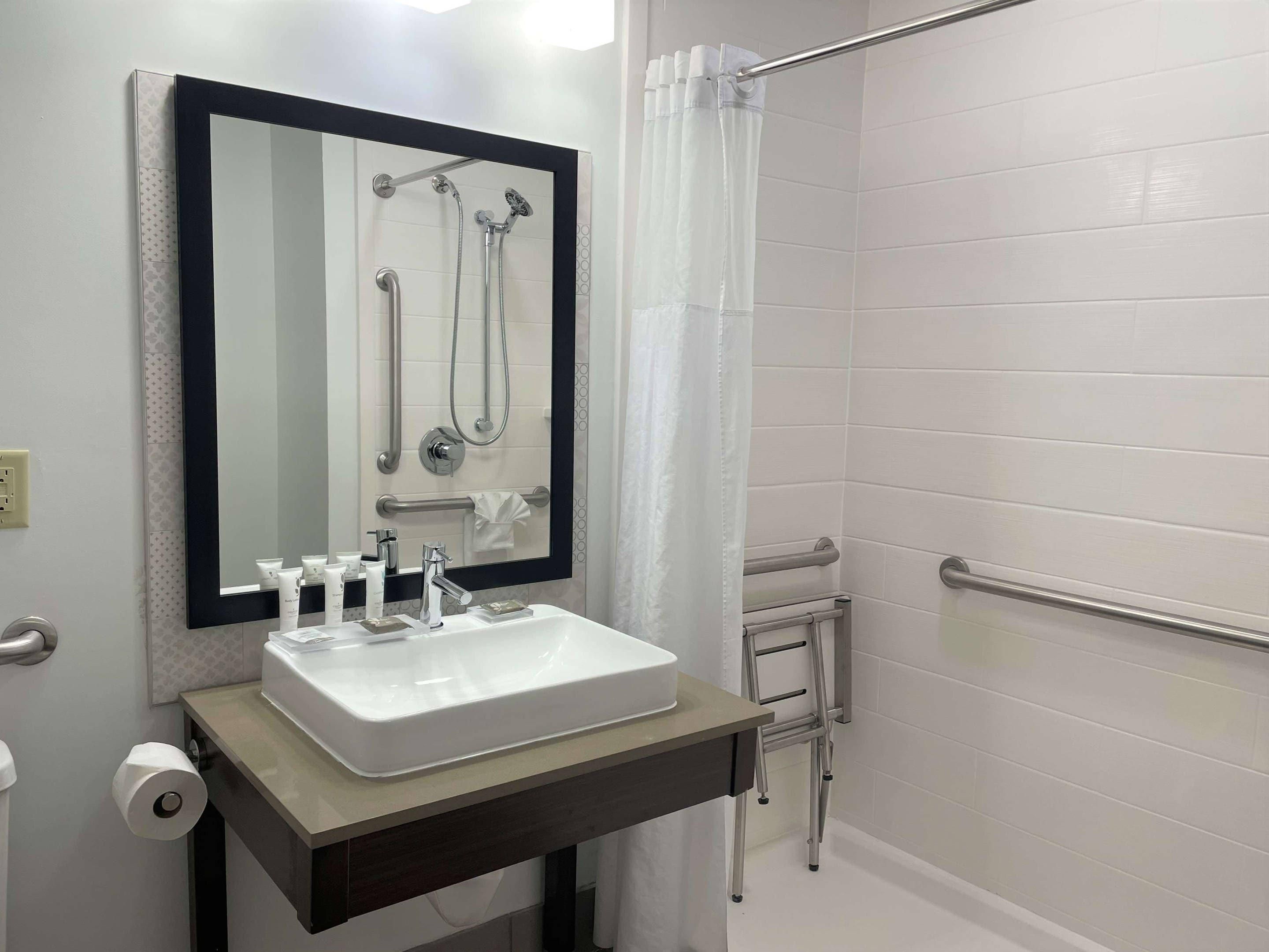 A bathroom with a white sink, mirror, and shower.