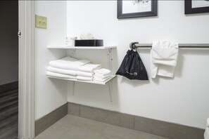 A bathroom with a white sink, a towel rack with folded towels, and a black bag hanging on the towel rack. - Country Inn & Suites by Radisson, Stone Mountain, GA (Stone Mountain)