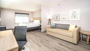 Una camera d'albergo con un letto, un divano, una scrivania e una sedia.