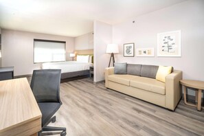 Habitació d'hotel amb llit, sofà, escriptori i cadira.