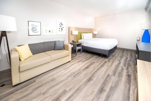 A hotel room with a bed, a sofa, a desk, and a lamp. - Country Inn & Suites by Radisson, Stone Mountain, GA (Stone Mountain)
