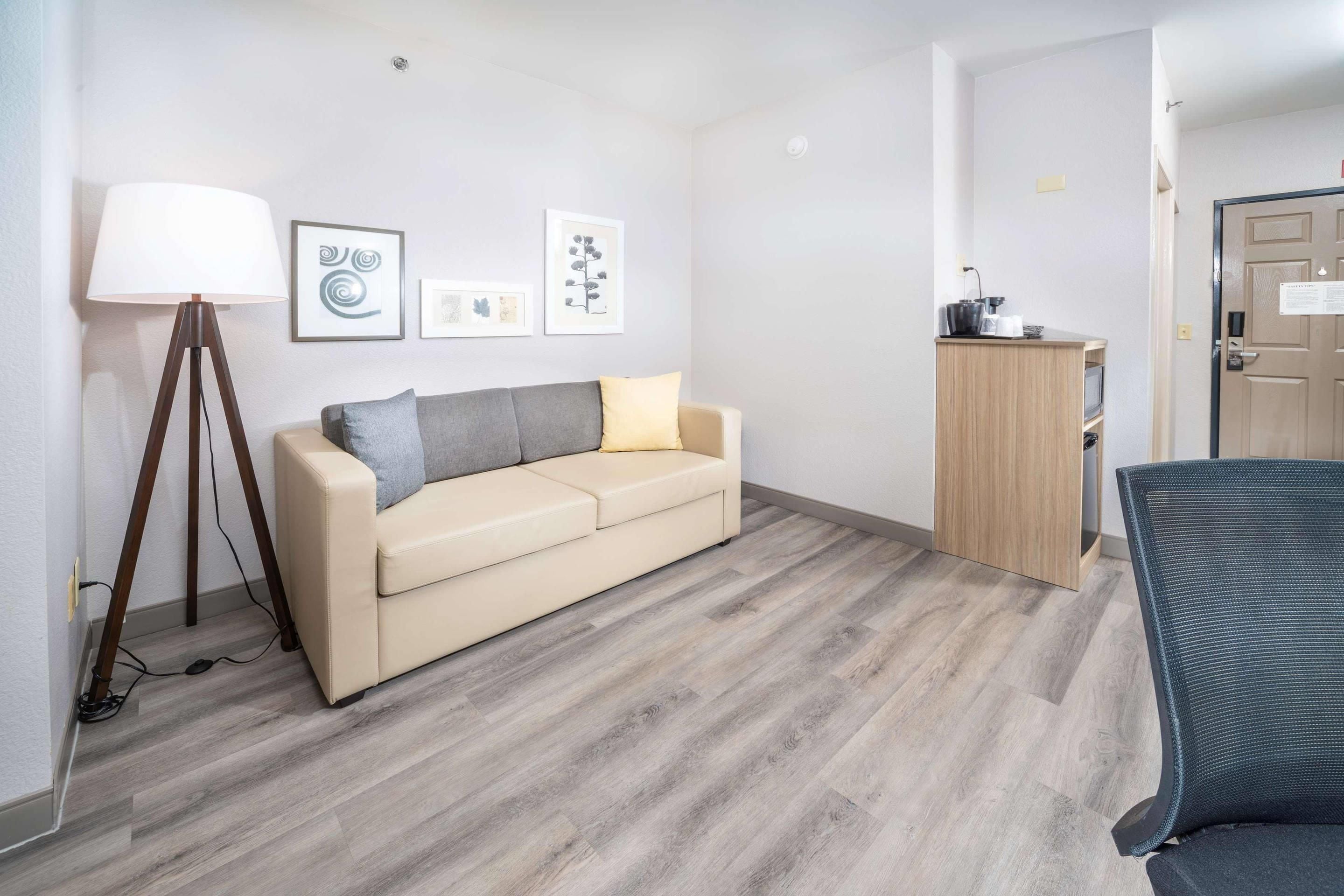 A room with a sofa, a desk, and a lamp.