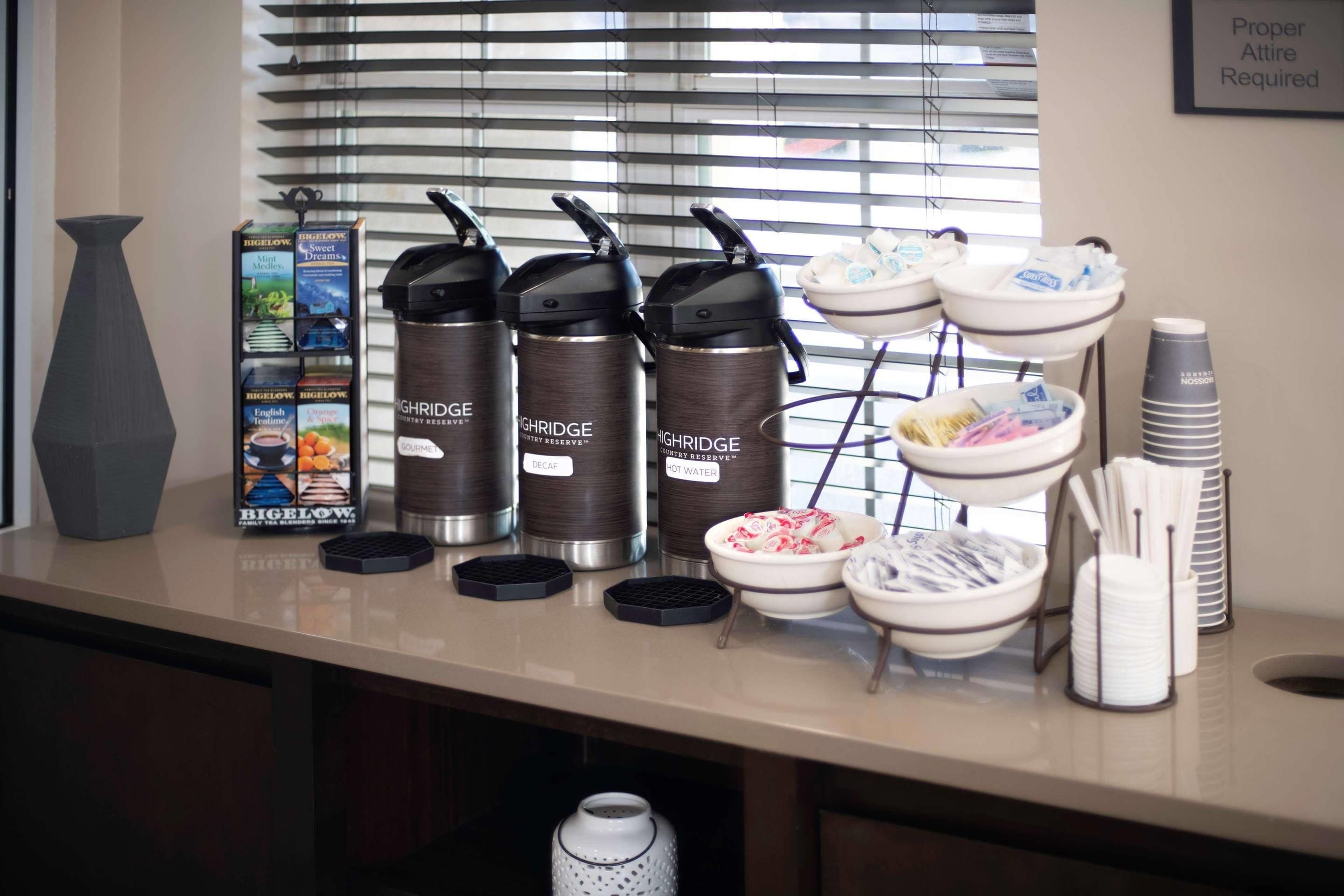 A counter with tea kettles, a tea box, and bowls of snacks.