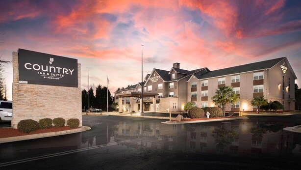 A Country Inn & Suites by Radisson building with a brick facade, multiple windows, and a parking lot. - Country Inn & Suites by Radisson, Stone Mountain, GA (Stone Mountain)