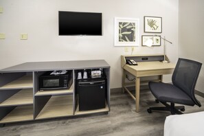 A hotel room with a flat-screen TV, a desk with a computer, a chair, a microwave, and a mini-fridge. - Country Inn & Suites by Radisson, Stone Mountain, GA (Stone Mountain)