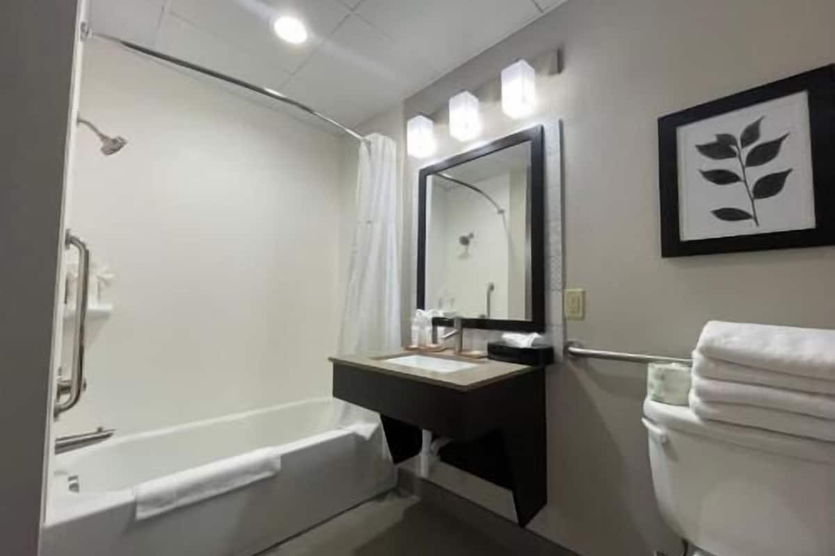 A bathroom with a bathtub, a sink with a mirror, and a toilet.