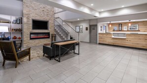 A modern lobby with a fireplace, a staircase, and a reception desk. - Country Inn & Suites by Radisson, Valdosta, GA (Valdosta)