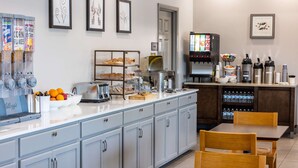 A breakfast bar with cereal dispensers, a coffee machine, and a beverage dispenser. - Country Inn & Suites by Radisson, Valdosta, GA (Valdosta)