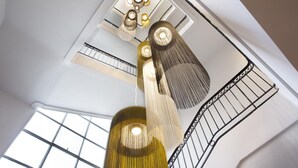 Un interior moderno con una columna central, una escalera con barandilla y un tragaluz.