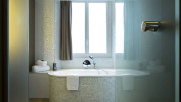 A modern bathroom with a freestanding bathtub, a glass shower enclosure, and a window providing natural light.