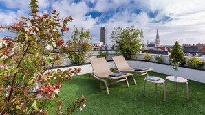 Terraza en la azotea con dos sillones de relax, una mesita y una planta en maceta.