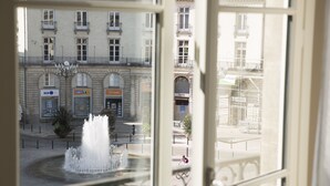 Vista de una fuente en una plaza pública con edificios al fondo.