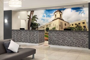 A reception area with a modern design, featuring a large poster of a building, a reception desk, and a seating area with a couch.