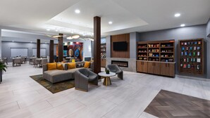 A modern lobby with a sofa, chairs, a fireplace, and a snack display. - La Quinta Inn & Suites by Wyndham Brownsville North (Brownsville)