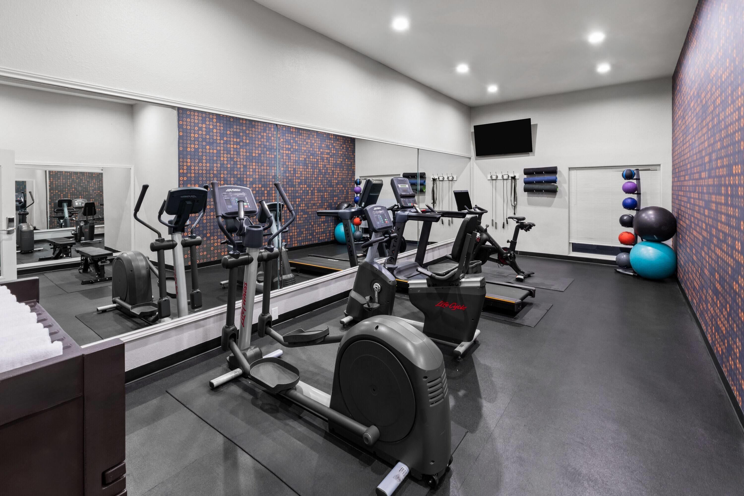 Ein Fitnessstudio mit Laufbändern, Kurzhanteln und Übungsbällen.