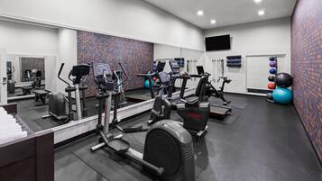Ein Fitnessstudio mit Laufbändern, Kurzhanteln und Übungsbällen.