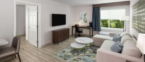 Uma sala de estar moderna com um sofá, uma mesa de centro, uma televisão e uma escrivaninha.