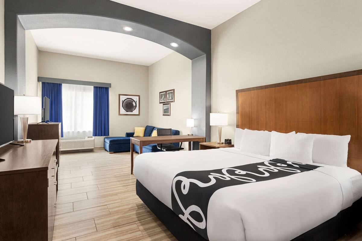 Ein Hotelzimmer mit einem großen Bett, einem Schreibtisch, einem Sessel, einer Couch und einem Fernseher.