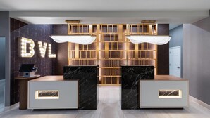 A reception area with a 'BYL' sign, two marble reception desks, a herringbone-patterned wall, and a herringbone-patterned floor. - La Quinta Inn & Suites by Wyndham Brownsville North (Brownsville)