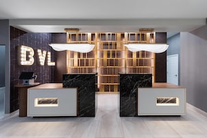 A reception area with a 'BYL' sign, two marble reception desks, a herringbone-patterned wall, and a herringbone-patterned floor.