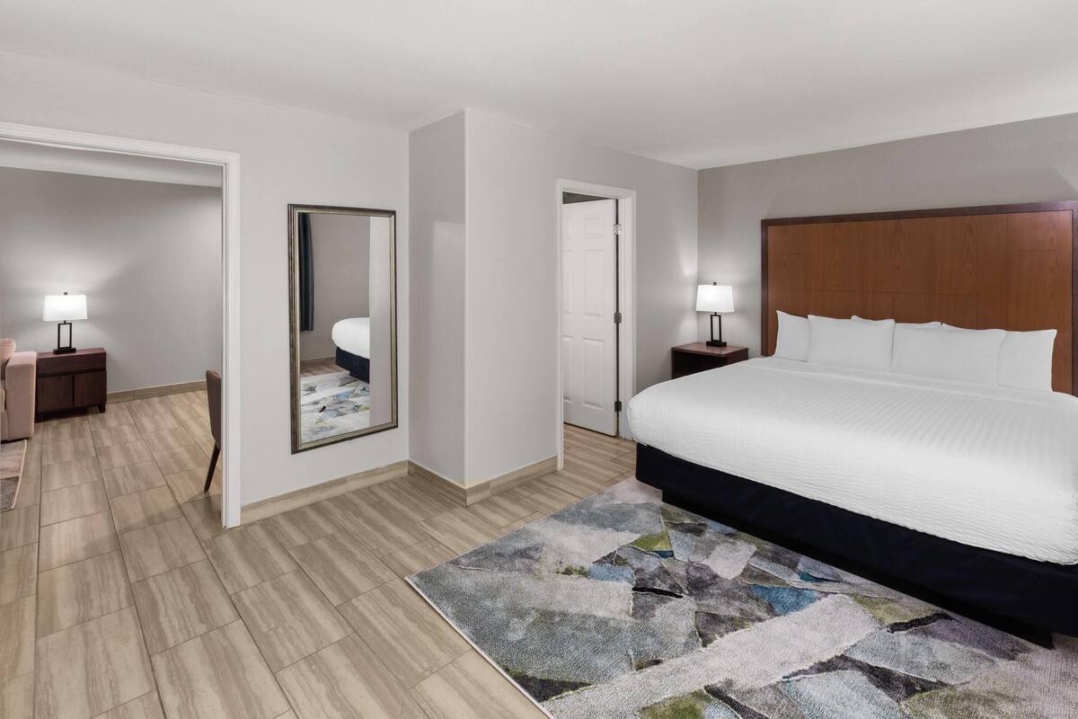 Ein Hotelzimmer mit Bett, Nachttischen, einem Spiegel und einer Tür.