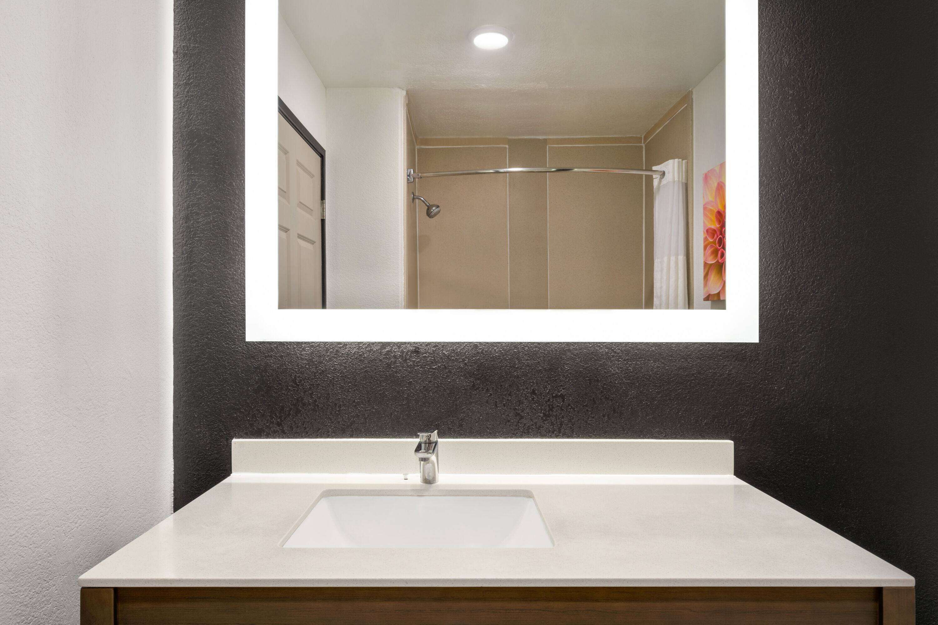 A bathroom with a white sink, a mirror, and a shower area.
