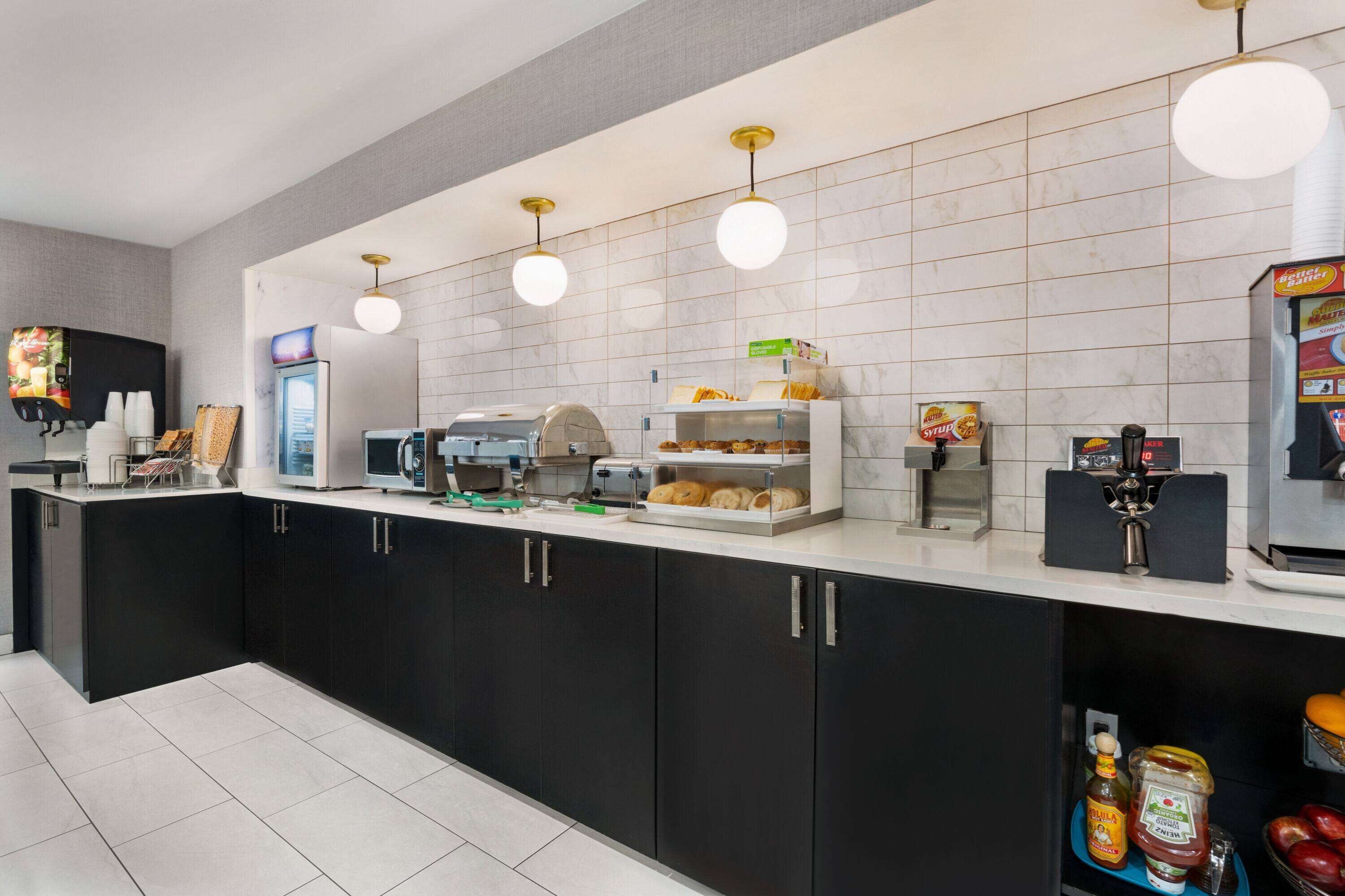 Una cocina moderna con cafetera, microondas y una vitrina para pan.