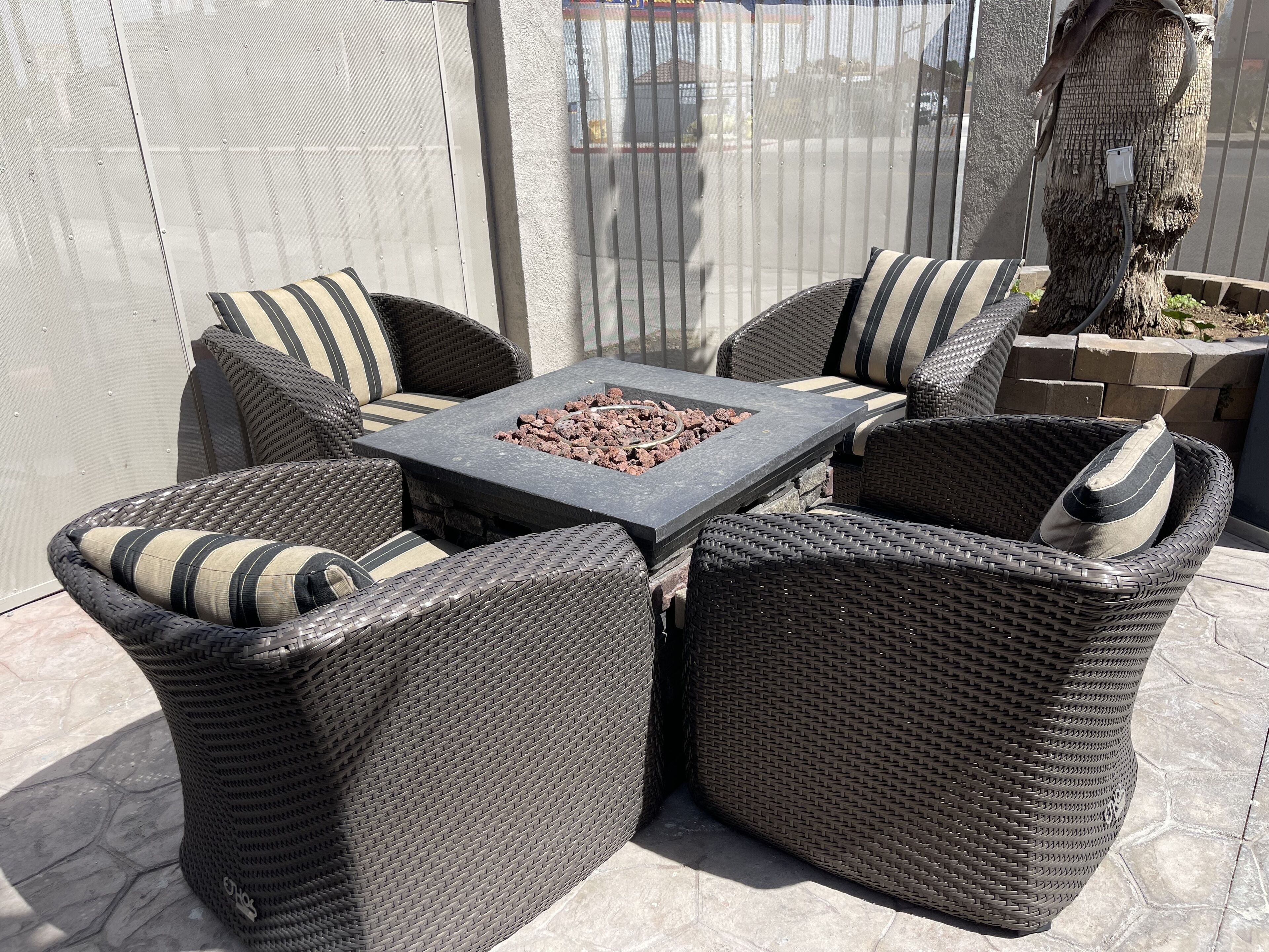 An outdoor seating area with wicker furniture and a central fire feature.