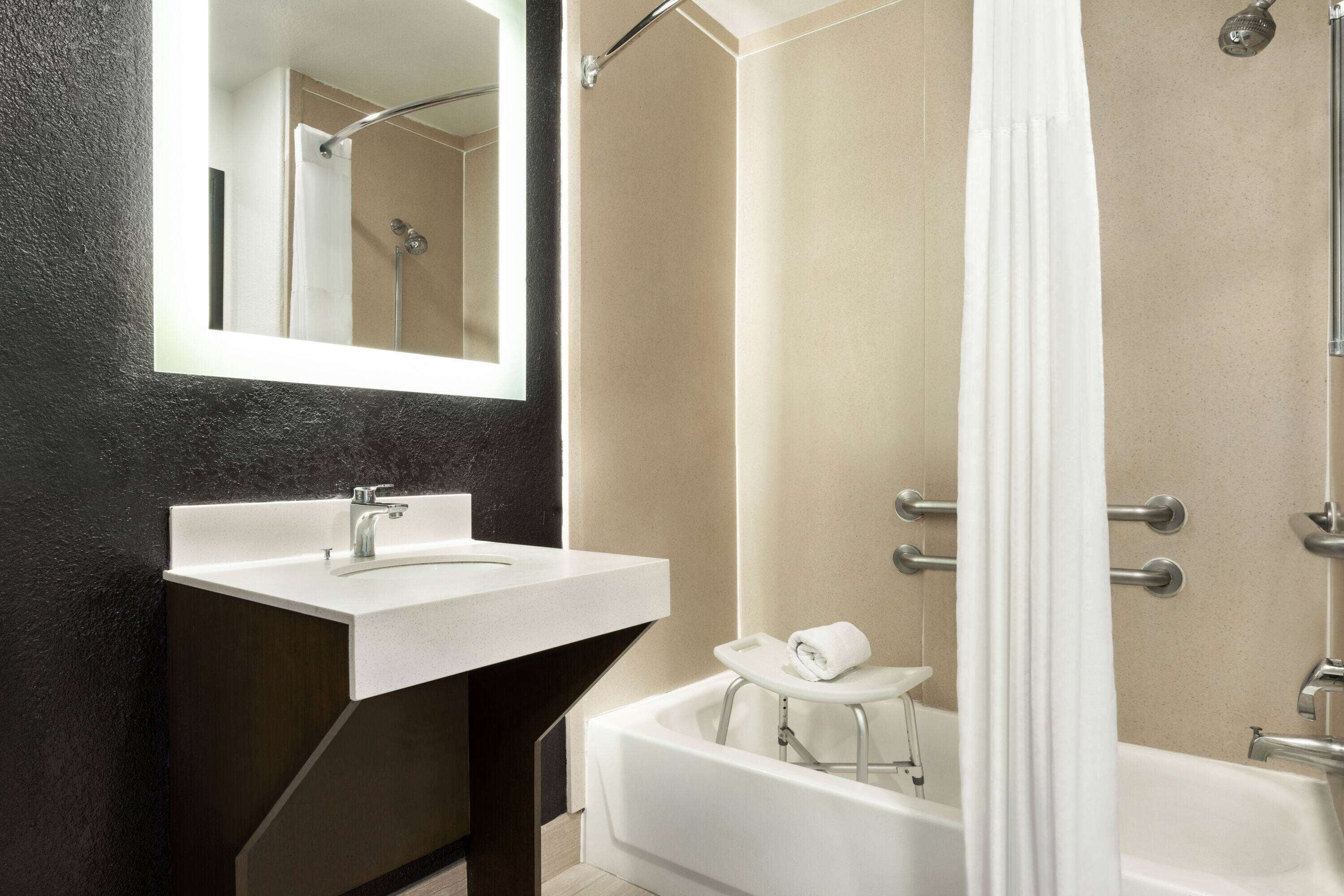 A modern bathroom with a white sink, a bathtub, and a shower.