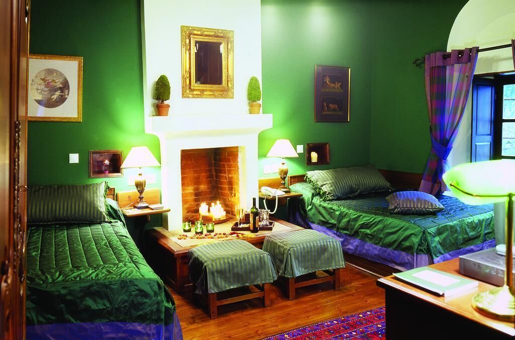 A room with two single beds, a fireplace, and a small table with a lamp.